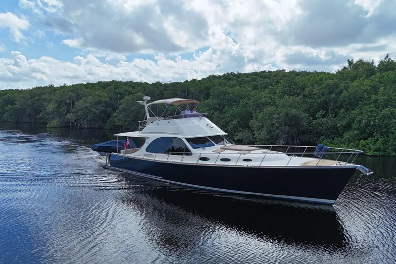 Slide: The Image of 2018 Palm Beach Motor Yachts PB55 Flybridge cruising on a serene river with lush greenery. - 70