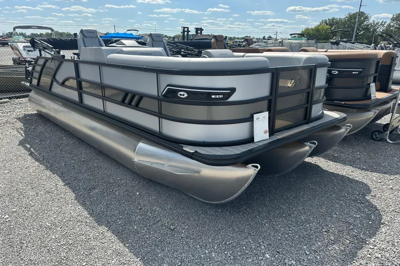 Slide: The Image of 2025 Bentley Pontoons 223 Elite Swingback, sleek design, parked on gravel lot. - 2