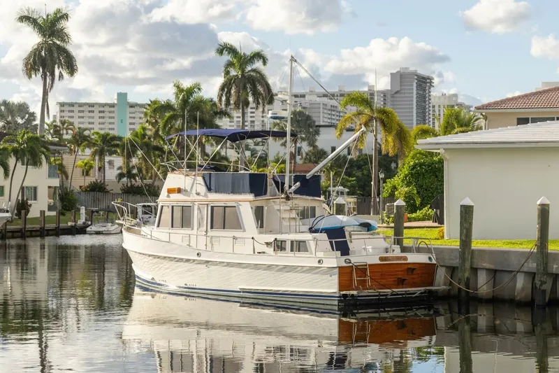 Slide: The Image of 1985 Grand Banks 42 Classic yacht docked by palm trees and buildings. - 1