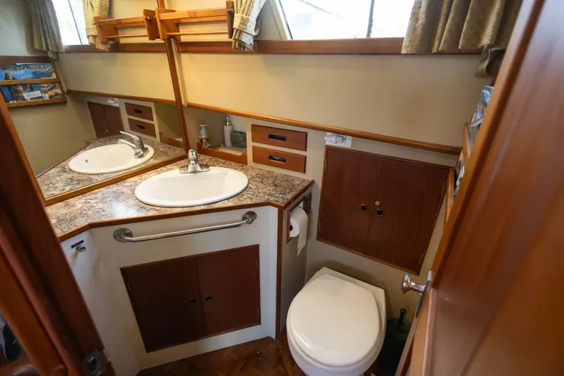 Slide: The Image of 1985 Grand Banks 42 Classic yacht bathroom with sink, toilet, and wooden cabinetry. - 14