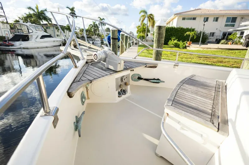 Slide: The Image of 1985 Grand Banks 42 Classic yacht deck with wooden seating and railing, docked near waterfront homes. - 25