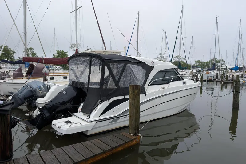 The Image of 2019 Beneteau Antares 23 boat docked in a marina, surrounded by sailboats. - 0