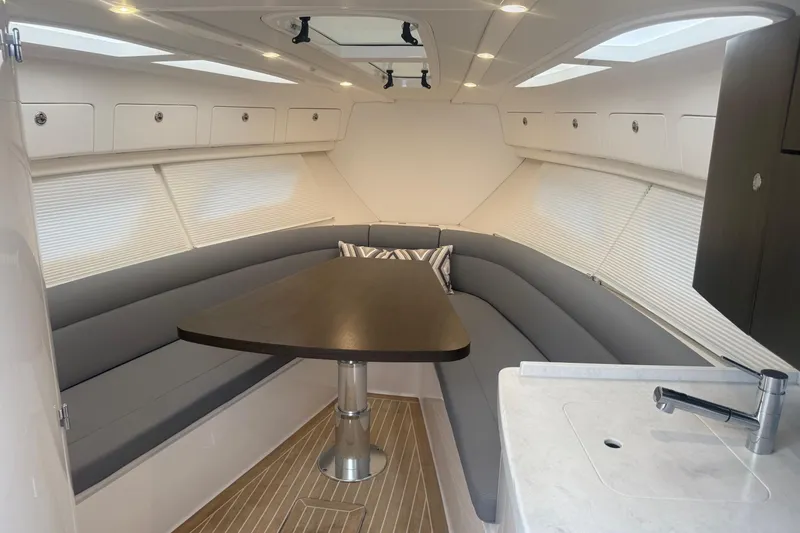Slide: The Image of 2021 Intrepid 409 Valor boat interior with white seating and table, docked on calm water. - 26
