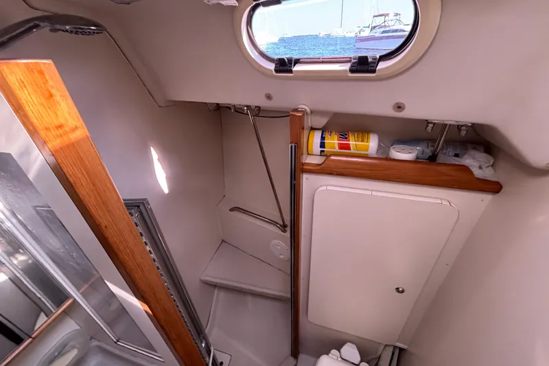 Slide: The Image of Interior of a 2004 Catalina 350 sailboat bathroom with storage and porthole view. - 16
