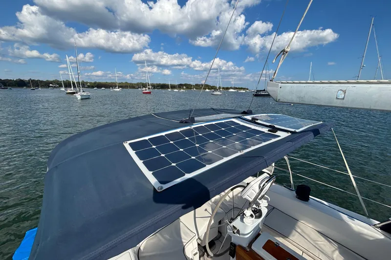Slide: The Image of Catalina 350 sailboat with solar panels, anchored in a scenic bay under a blue sky. - 24