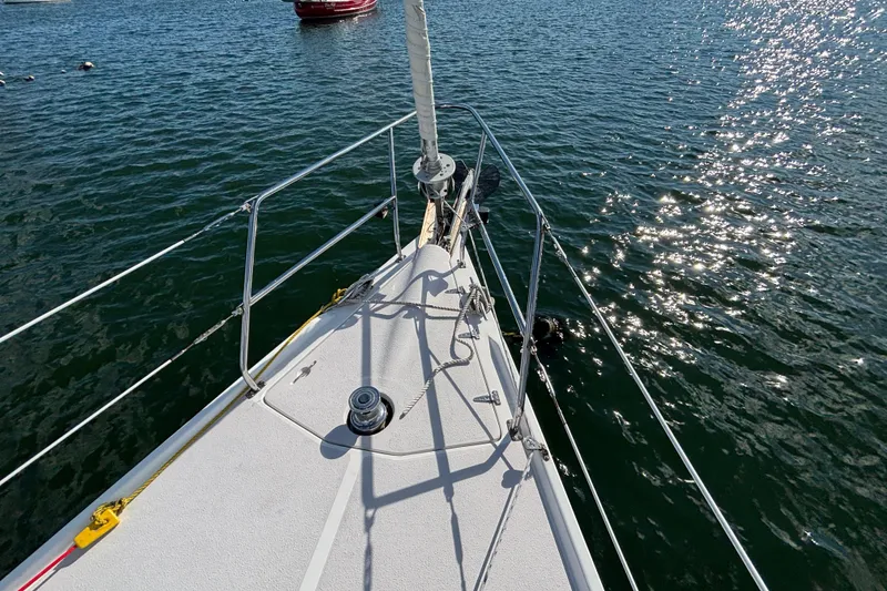 Slide: The Image of Bow of 2004 Catalina 350 sailboat on sparkling water, with visible railing and winch. - 28