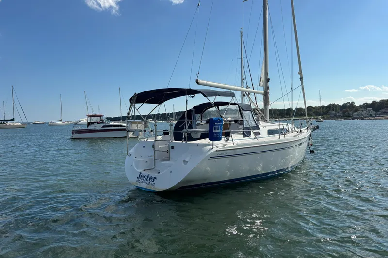 Slide: The Image of 2004 Catalina 350 sailboat named "Jester" anchored in a scenic harbor. - 37