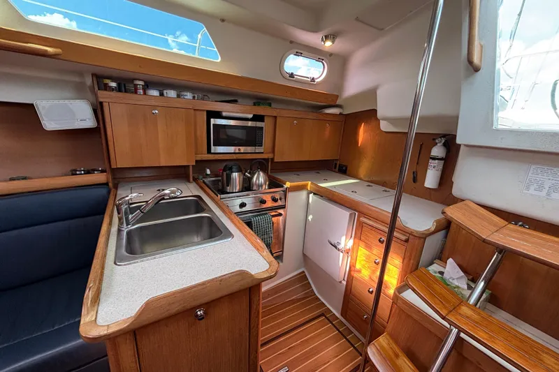 Slide: The Image of 2004 Catalina 350 yacht interior with kitchen, wooden cabinets, and appliances. - 6