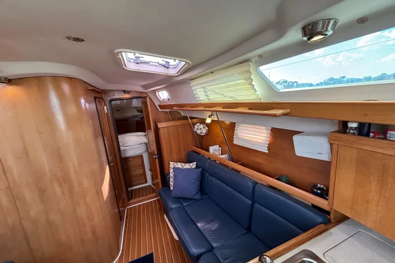 Slide: The Image of Interior of a 2004 Catalina 350 sailboat with wooden finishes and blue seating. - 7