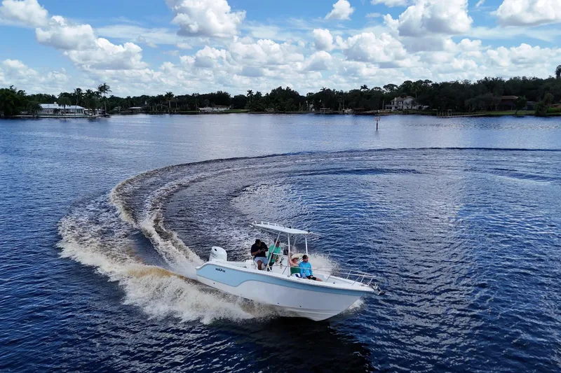 The Image of 2009 Sea Fox 230 Center Console boat making a sharp turn on a scenic lake. - 0