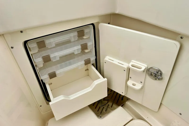 Slide: The Image of 2026 Scout 288 LXF boat storage compartment with open drawers and secure latch. - 20
