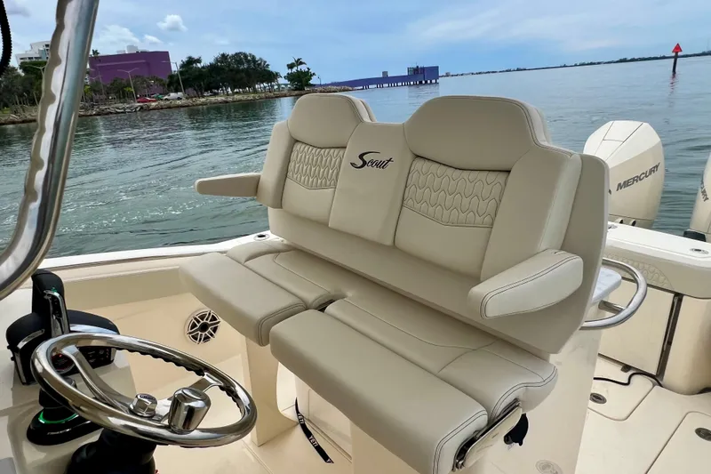 Slide: The Image of 2026 Scout 288 LXF boat interior with luxurious seating and steering wheel, docked by the water. - 25