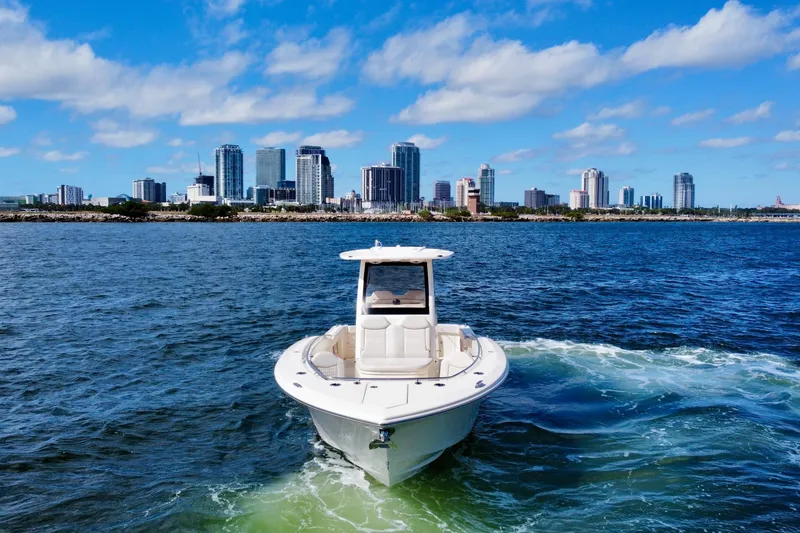 Slide: The Image of 2026 Scout 288 LXF boat cruising near city skyline on a sunny day. - 3