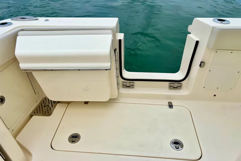 Slide: The Image of 2026 Scout 288 LXF boat deck with open transom door, near water. - 34