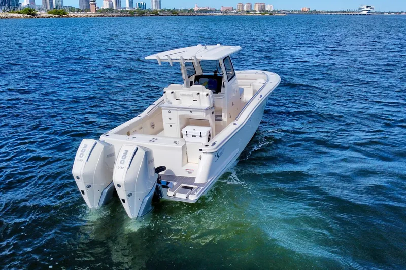 Slide: The Image of 2026 Scout 288 LXF boat cruising on open water with city skyline in background. - 6