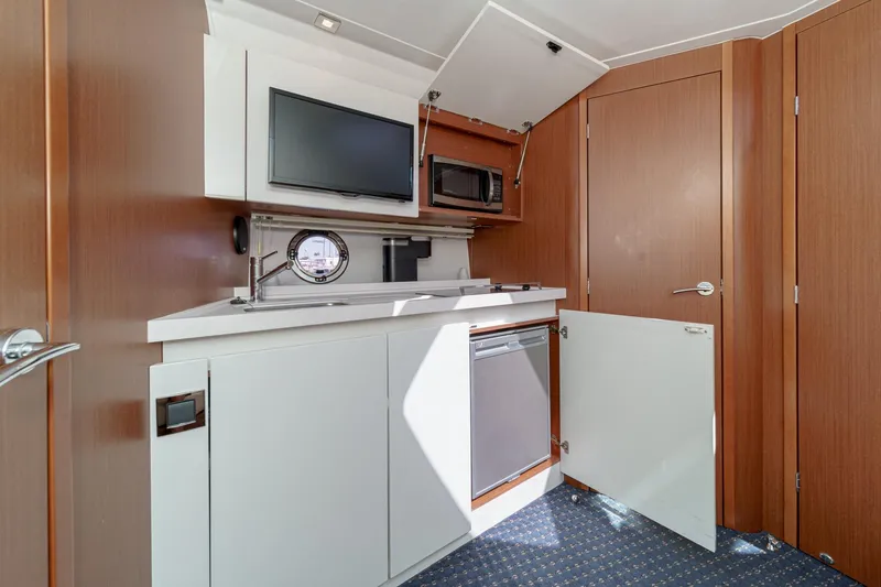 Slide: The Image of 2014 Beneteau Gran Turismo 38 yacht interior with kitchenette, featuring microwave and TV. - 41