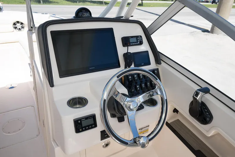 Slide: The Image of 2023 Grady-White Freedom 235 boat dashboard with steering wheel and navigation controls. - 18