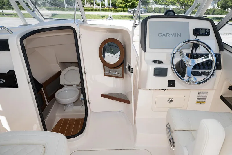 Slide: The Image of 2023 Grady-White Freedom 235 boat interior with helm, Garmin display, and compact toilet. - 19