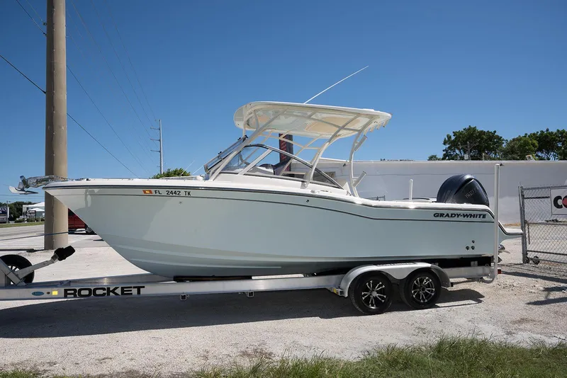 Slide: The Image of 2023 Grady-White Freedom 235 boat on trailer, parked outdoors under clear blue sky. - 2