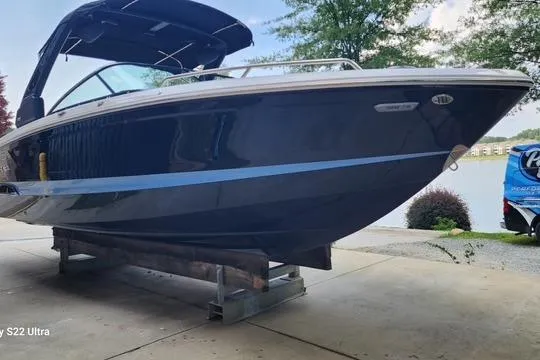 Slide: The Image of 2023 Chaparral 267 SSX boat docked with black cover and canopy. - 2