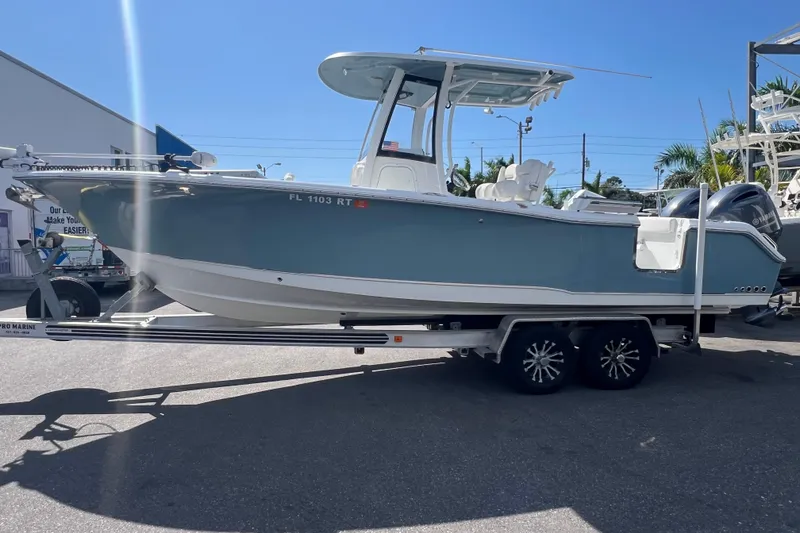 Slide: The Image of 2019 Sea Hunt Gamefish 25 boat on trailer, parked outdoors under clear blue sky. - 2