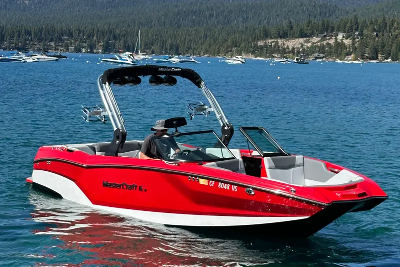 The Image of 2021 MasterCraft NXT24 boat on a scenic lake with forested hills. - 0