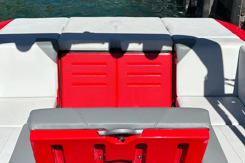 Slide: The Image of 2021 MasterCraft NXT24 boat interior with red and gray seating, docked by water. - 10