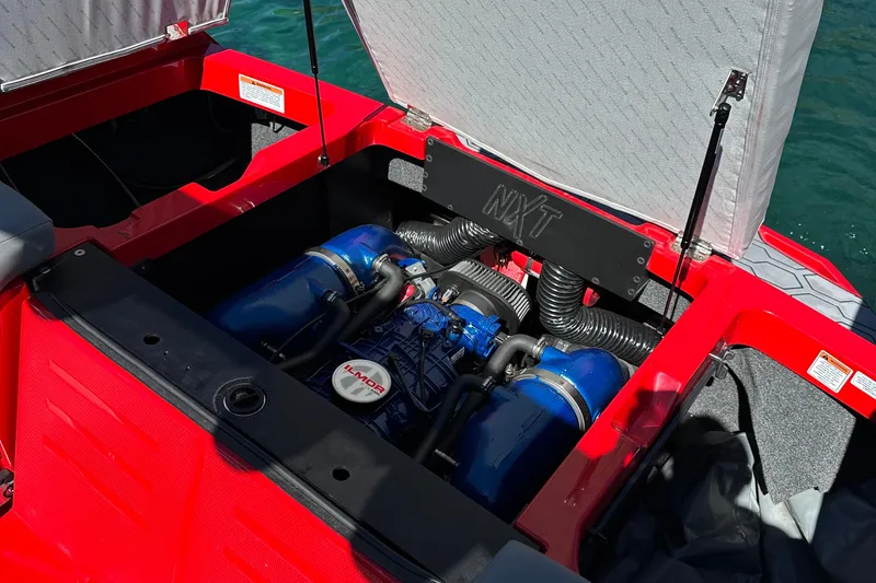 Slide: The Image of 2021 MasterCraft NXT24 boat engine compartment with Ilmor engine, open hatch, and red interior. - 18