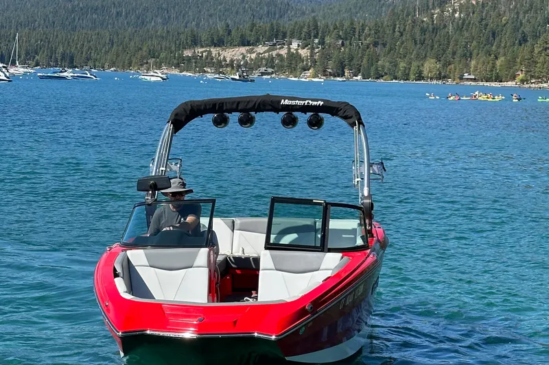 Slide: The Image of 2021 MasterCraft NXT24 boat on a scenic lake with forested hills in the background. - 4