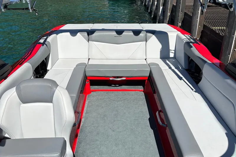 Slide: The Image of 2021 MasterCraft NXT24 boat interior with gray and red seating near dock. - 6