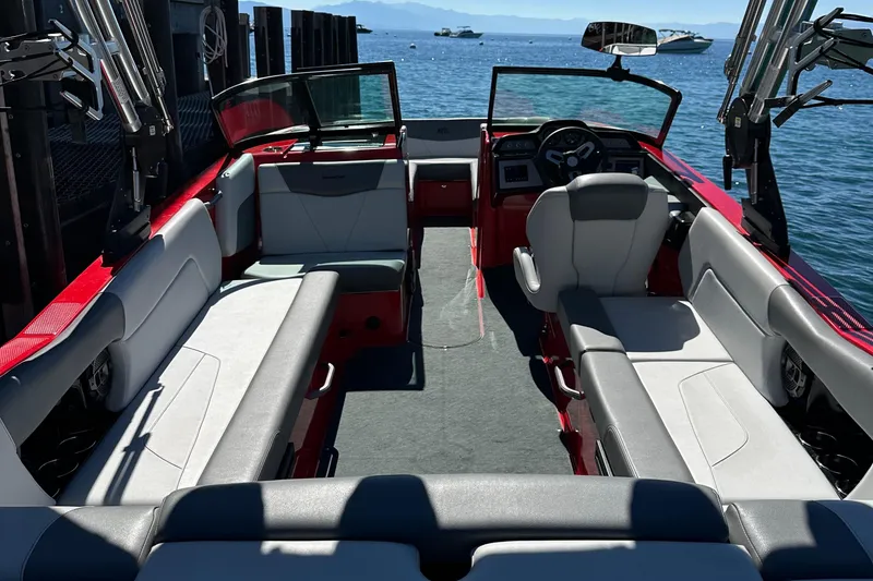 Slide: The Image of 2021 MasterCraft NXT24 boat interior with red and gray seating, docked by the water. - 8