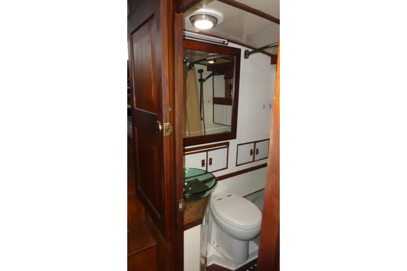 Slide: The Image of 1979 Hiptimco 40' Trawler bathroom with wooden door, glass sink, and toilet. - 21