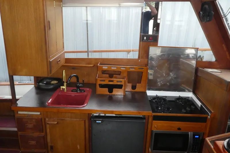 Slide: The Image of 1979 Hiptimco 40' Trawler kitchen with wooden cabinetry, red sink, and stove. - 8