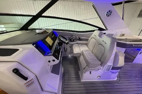 Slide: The Image of 2021 Sea Ray 320 Sundancer helm with modern controls and dual seating in a sleek interior. - 3