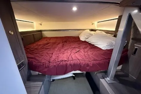 Slide: The Image of 2021 Sea Ray 320 Sundancer cabin with cozy bed and red bedding. - 6