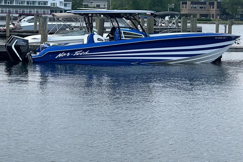 The Image of 2025 Nor-Tech 340 Sport Center Console boat docked, featuring sleek blue and white design. - 17