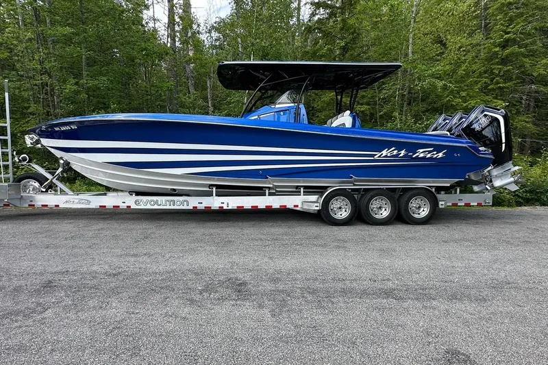 Slide: The Image of 2025 Nor-Tech 340 Sport Center Console boat on trailer, blue with white stripes, parked outdoors. - 20