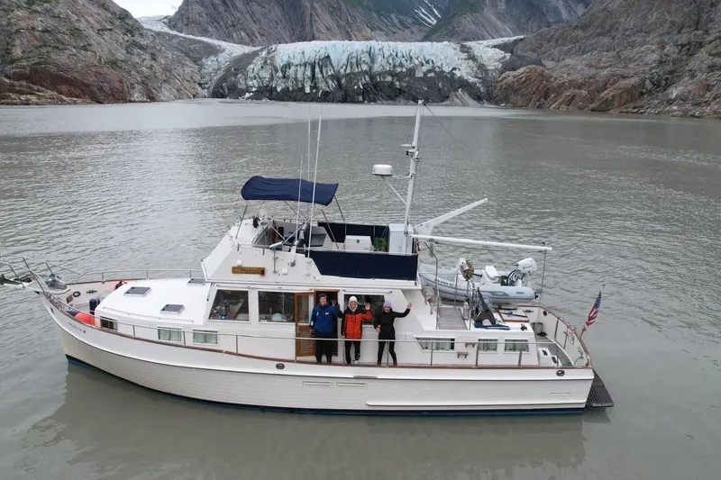 The Image of Grand Banks Classic 1990 yacht near glacier, with people on deck, in scenic waterway. - 0