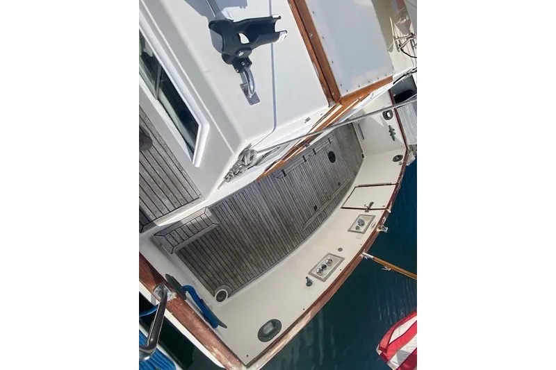Slide: The Image of 1990 Grand Banks Classic boat deck with wooden flooring and American flag. - 22
