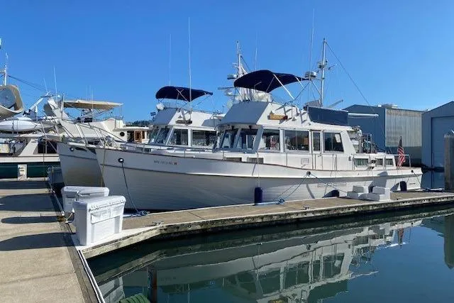 Slide: The Image of 1990 Grand Banks Classic yacht docked at marina, reflecting on calm water under clear blue sky. - 23