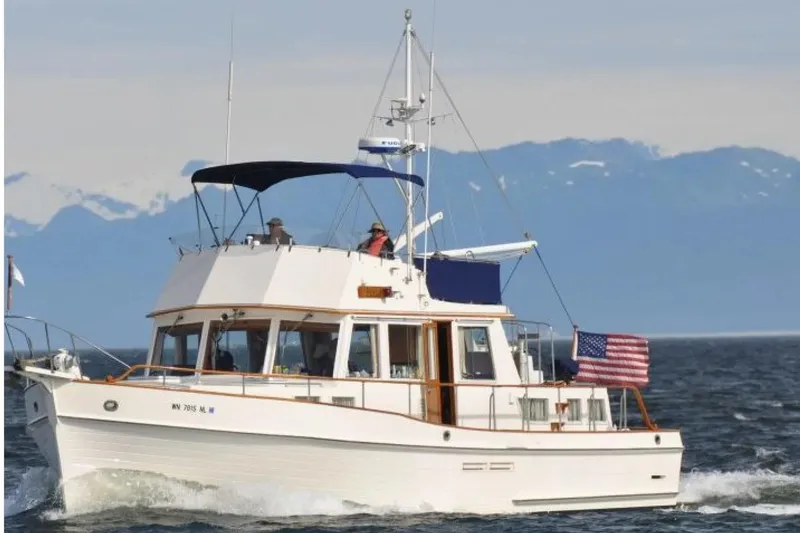 Slide: The Image of 1990 Grand Banks Classic yacht cruising on open water with mountains in the background. - 24