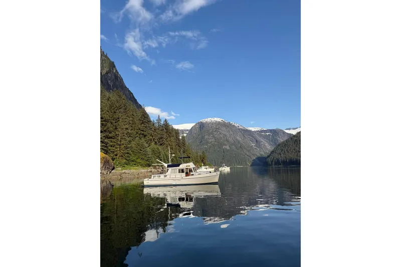 Slide: The Image of 1990 Grand Banks Classic yacht on serene lake with mountain backdrop. - 25
