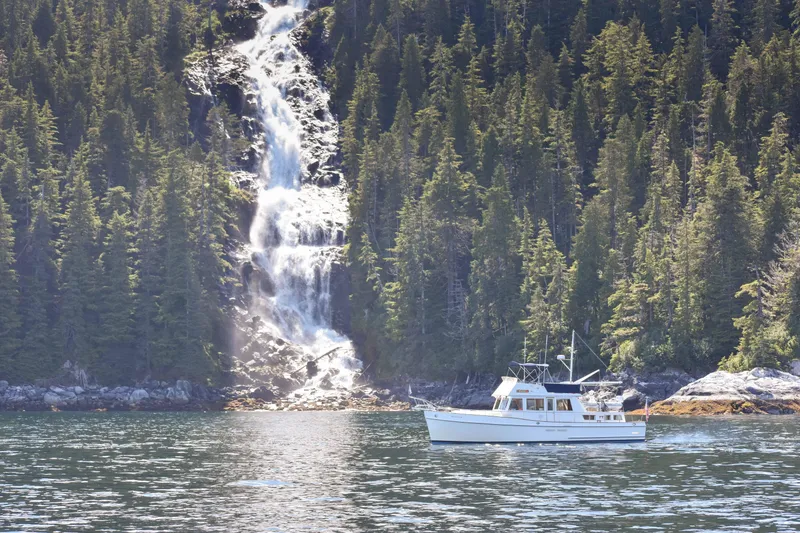 Slide: The Image of 1990 Grand Banks Classic boat near a forest waterfall, serene natural setting. - 26