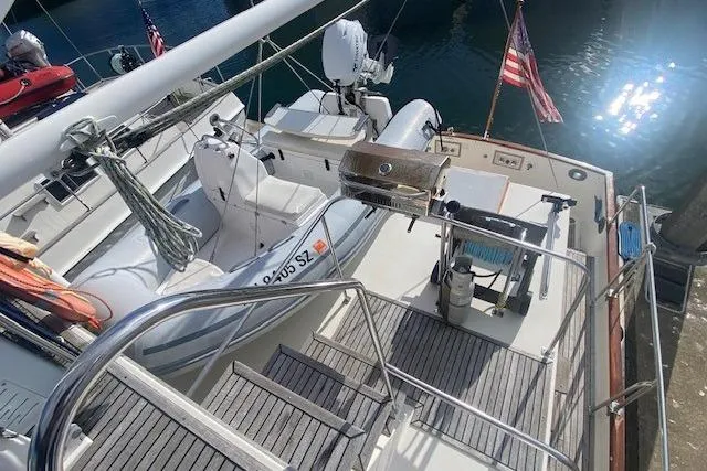 Slide: The Image of 1990 Grand Banks Classic yacht deck with dinghy and American flag in marina. - 4