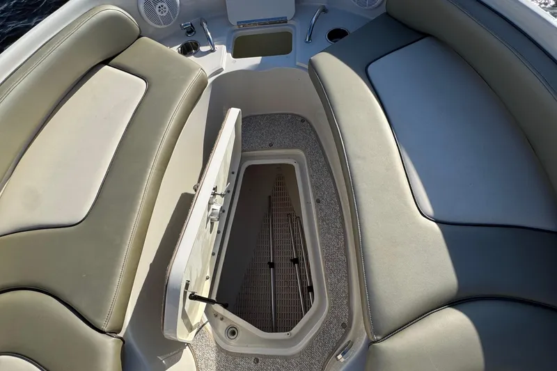 Slide: The Image of 2005 Sea Ray 240 Sundeck interior with open storage compartment and cushioned seating. - 15