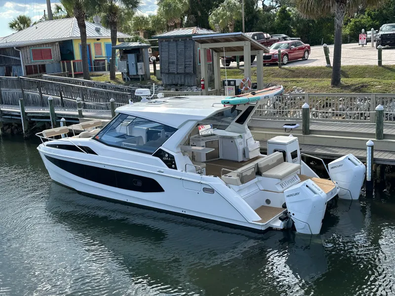 Slide: The Image of 2025 Aquila 36 Sport boat docked, featuring sleek design and twin Mercury engines. - 1
