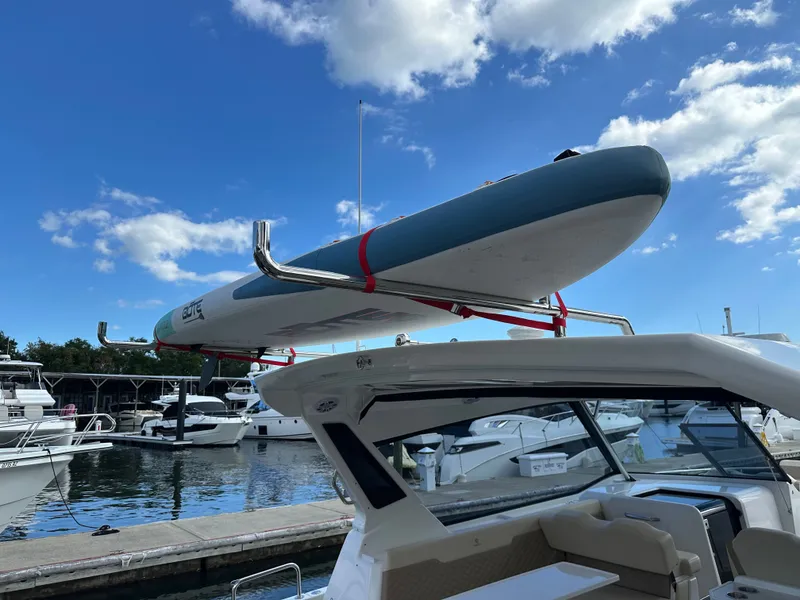 Slide: The Image of 2025 Aquila 36 Sport with paddleboard on roof, docked at marina under blue sky. - 11