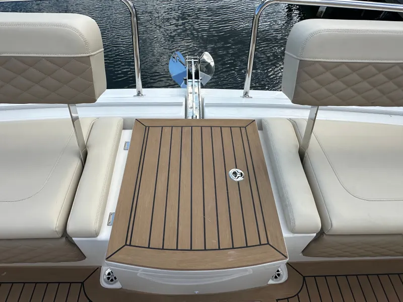 Slide: The Image of Aquila 36 Sport 2025 boat seating with wooden table, docked by water. - 20