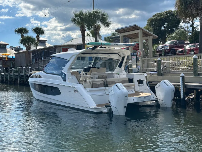 Slide: The Image of 2025 Aquila 36 Sport boat docked by a wooden pier under a partly cloudy sky. - 3