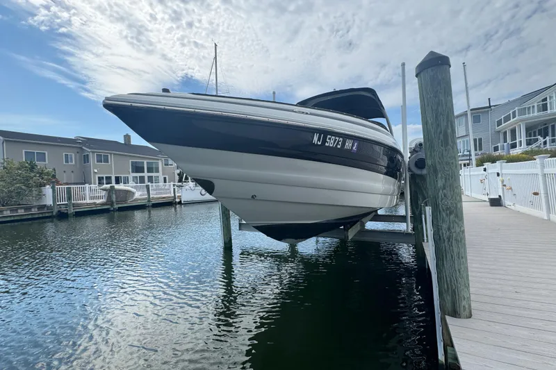 Slide: The Image of 2015 Crownline 285 SS boat docked on a lift by waterfront homes. - 12